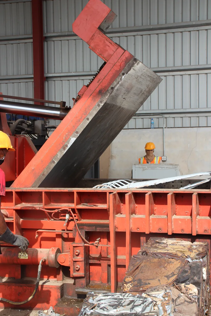 The CEVONS baling press with its jaw raised, being loaded with scrap metal