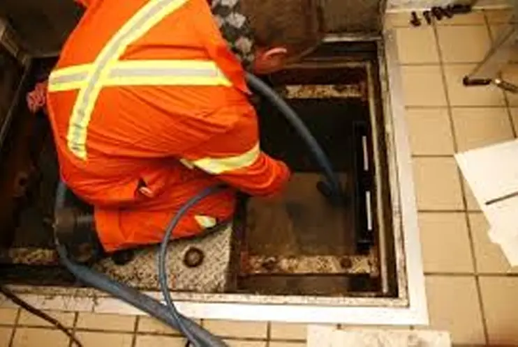 CEVONS crew servicing a commercial grease trap at a restaurant kitchen